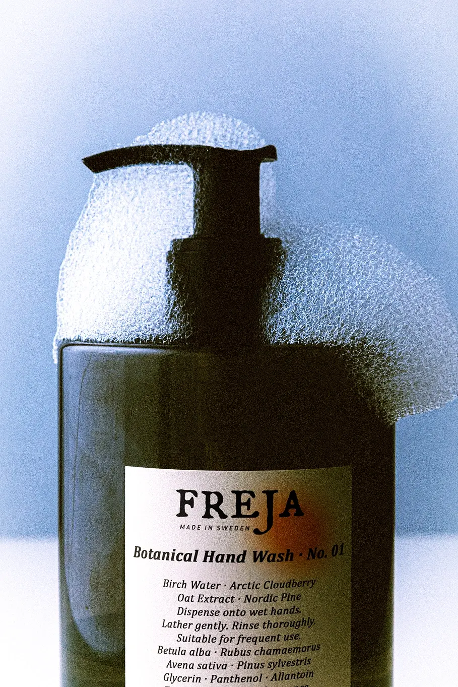 Freja botanical hand wash bottle against a pale blue background