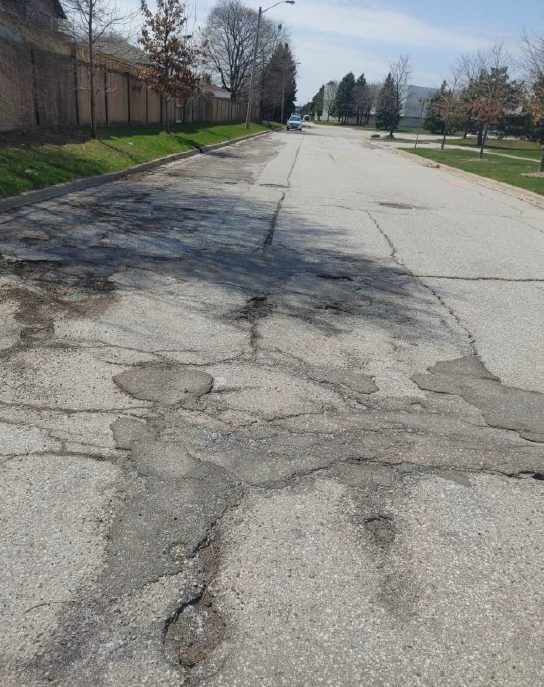 2-Ground-level photo of the cracked, deteriorated asphalt before reconstruction