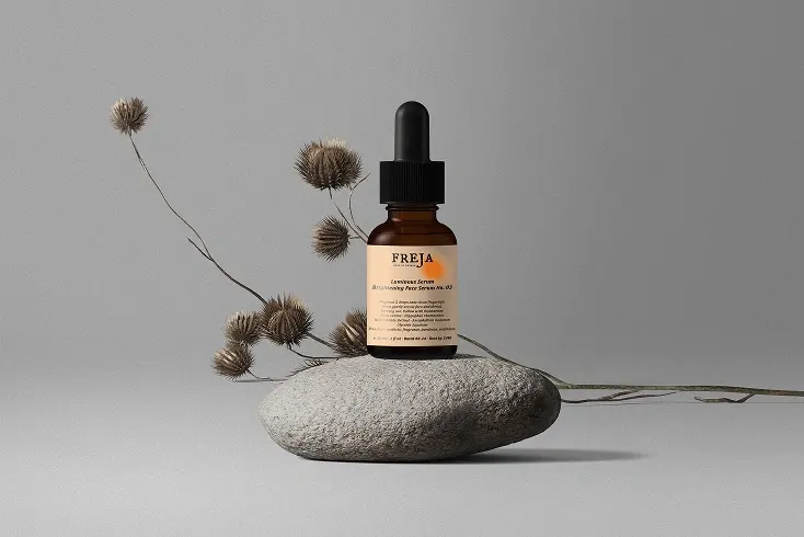 Freja dropper bottle balanced on a stone with dried branches